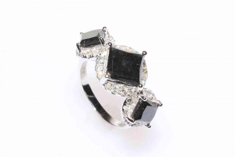 14 carat white gold black diamond trilogy ring featuring three square cut black diamonds, approximate 5.00 carat total diamond weight, and forty eight round brilliant cut white diamonds, approximate total diamond weight 0.59 carats.