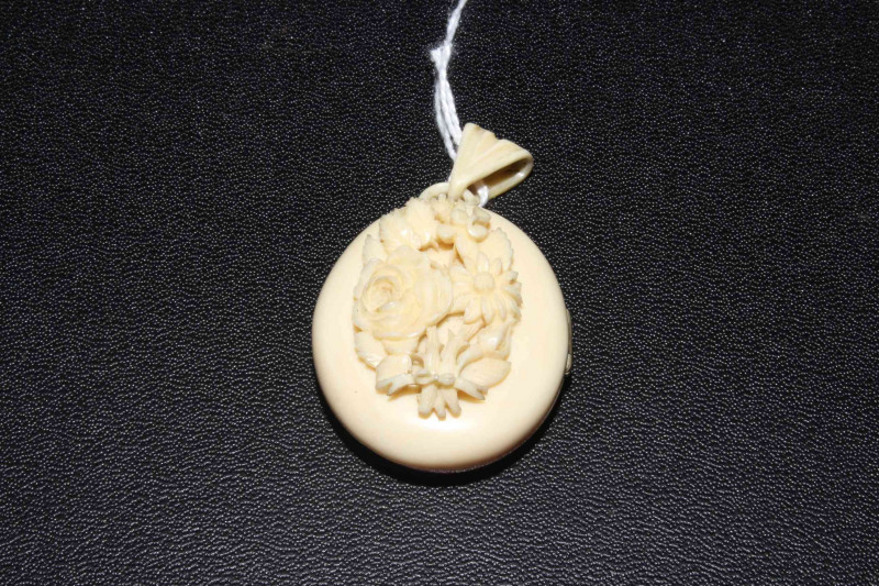 Victorian ivory pendant locket with carved bouquet.