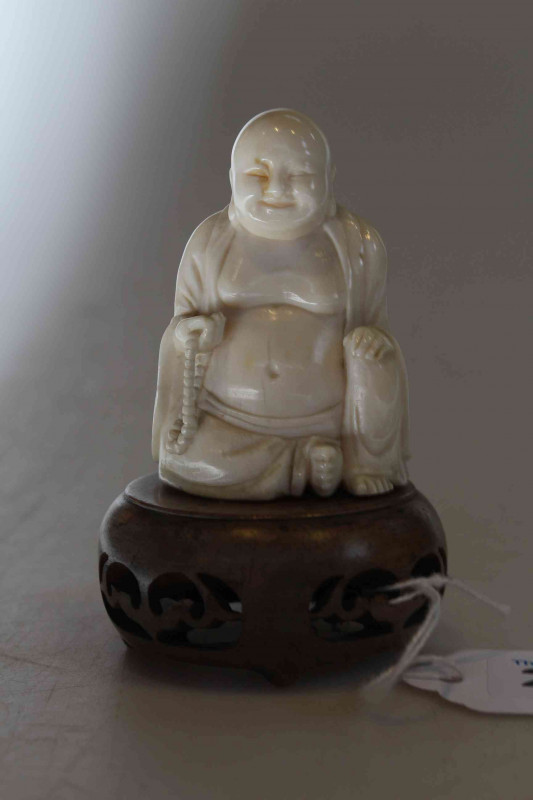 Antique ivory Buddha, the well carved seated figure holding beads, 6cm, with wood stand, and two ebony elephants (3).