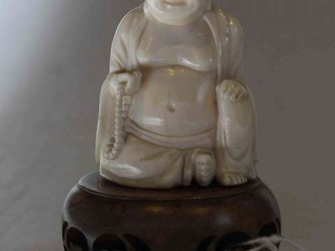 Antique ivory Buddha, the well carved seated figure holding beads, 6cm, with wood stand, and two ebony elephants (3). thumbnail