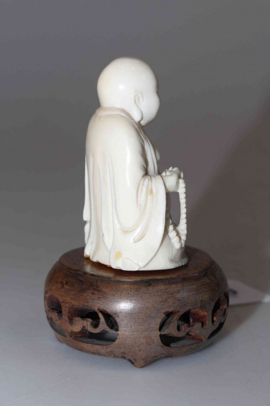 Antique ivory Buddha, the well carved seated figure holding beads, 6cm, with wood stand, and two ebony elephants (3).
