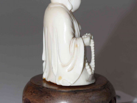 Antique ivory Buddha, the well carved seated figure holding beads, 6cm, with wood stand, and two ebony elephants (3). thumbnail