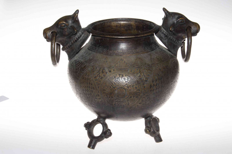 Islamic engraved bronze pot raised on three ring style feet with bull and ring handles.
