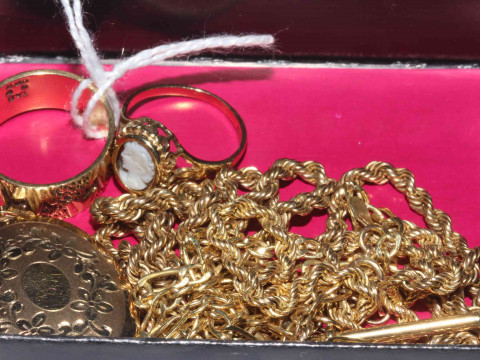 Box with gold chains, rings and locket.