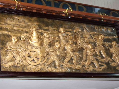 Embossed wall panel of Oriental children framed, 42cm by 223cm overall.