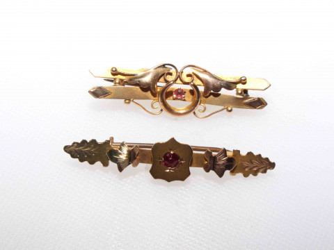 Two 9 carat gold coloured brooches with red stones.