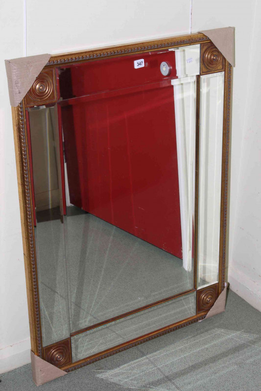 Gilt framed bevelled wall mirror with roundels to each corner, 100cm by 75cm overall.