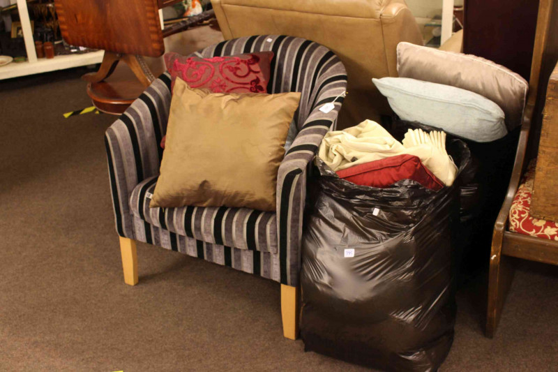 Contemporary tub chair in striped fabric, scatter cushions and curtains.