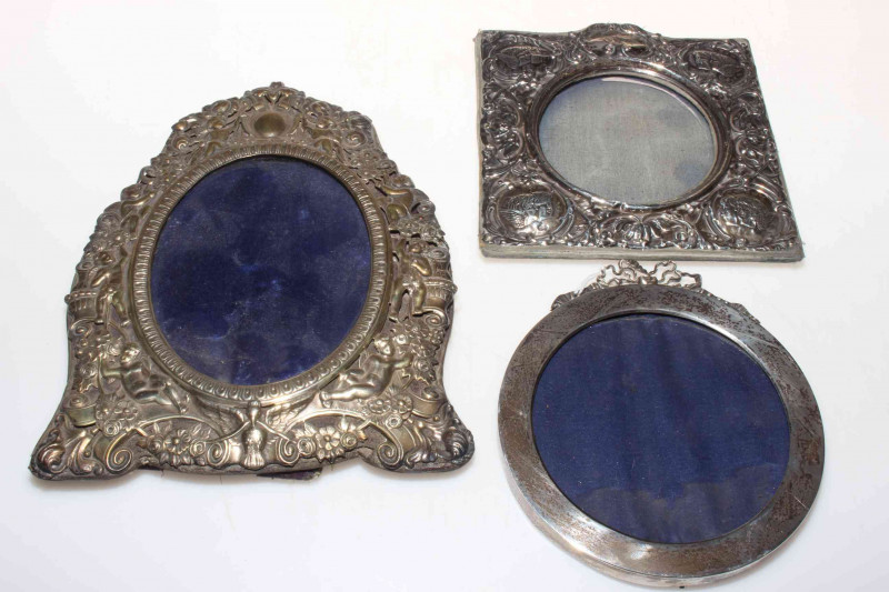 William Comyns silver easel photograph frame, pierced and embossed with cherubs, foliage and scrolls, 23cm by 17cm; and two other silver frames (3).