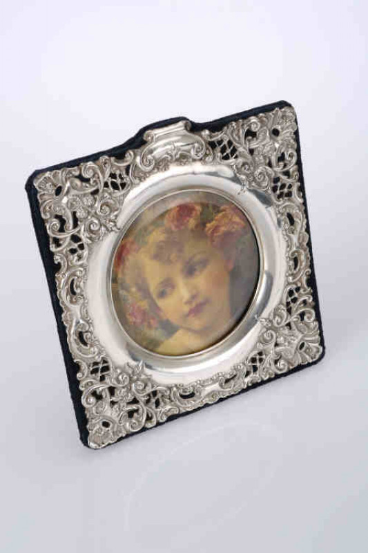 A late Victorian silver photograph frame, Chester 1900, the square pierced silver mount, chased with scrolls and foliage, enclosing a circular aperture, easel back. 16.5cm by 15.5cm