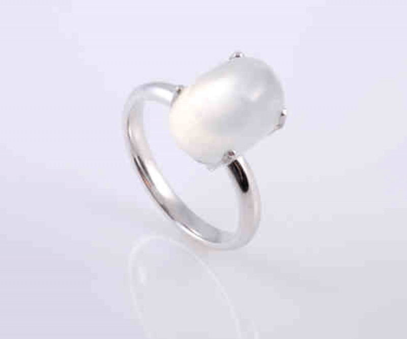A moonstone ring, the oval cabochon cut moonstone four claw set in white gold above a pierced mount on plain shoulders, marked for 18 carat gold. Ring size V