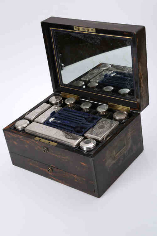 A mid Victorian coromandel vanity case, retailed by William Leuchars, the hinged rectangular lid opening to reveal a mirrored underside and an interior fitted with silver plate topped boxes, jars and bottles, fitted with a base drawer, Mordan locks. 19cm 