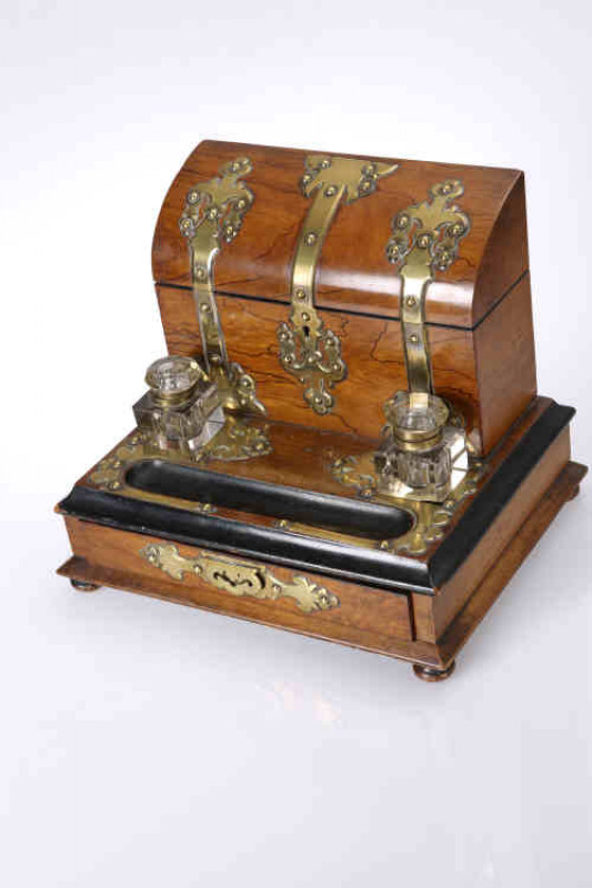 A Victorian walnut and brass stationery box, with correspondence box superstructure over a platform fitted with a pair of glass inkwells, pen well and frieze drawer, raised on bun feet. 26cm by 31cm by 25cm