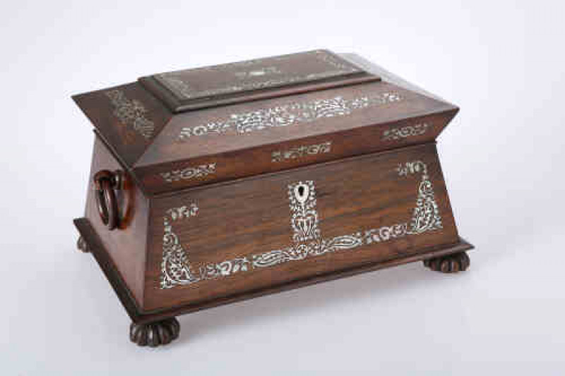 A George IV rosewood and mother of pearl jewellery casket, the projecting caddied lid above a tapering case with ring handles and raised on reeded bun feet, inlaid throughout with bands of foliage. 18cm by 32cm by 24cm