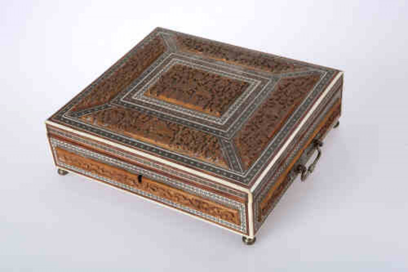 An Anglo-Indian rosewood and ivory work box, circa 1830, the hinged rectangular lid opening to reveal a mirror fitted to the underside and a hinged velvet lined box lid and covered compartments, characteristically carved and inlaid with white and stained 