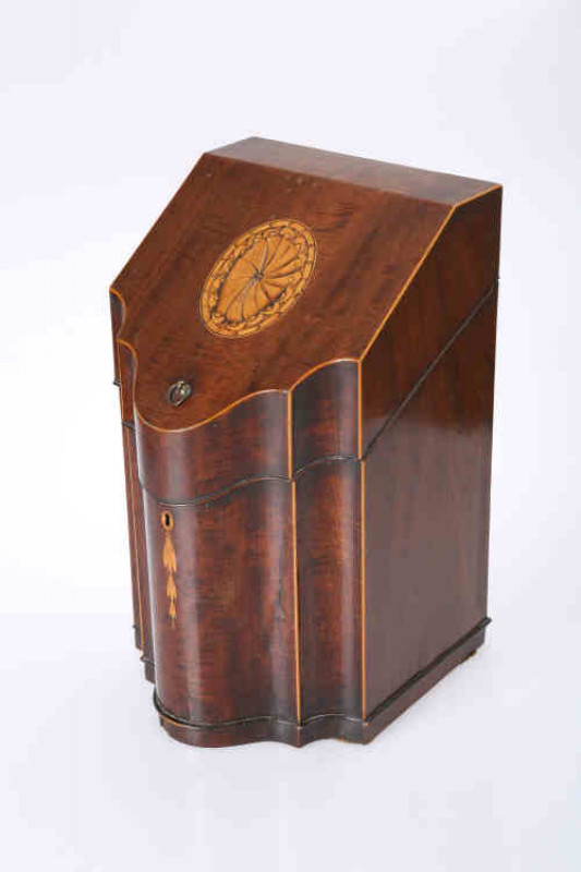 A Sheraton period mahogany and inlaid knife box, the hinged sloping lid, centred by an inlaid oval panel, opening to reveal a vacant lead lined interior, above a conforming serpentine front inlaid with pendant flowers issuing from an inlaid escutcheon. 39