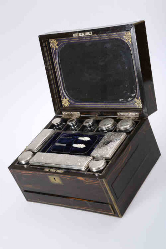 A fine Victorian coromandel dressing case, the hinged rectangular lid opening to reveal a mirrored underside and an interior fitted with silver topped jars and bottles, London 1861, the tops engraved with scrolls and foliage, above a concealed jewellery d