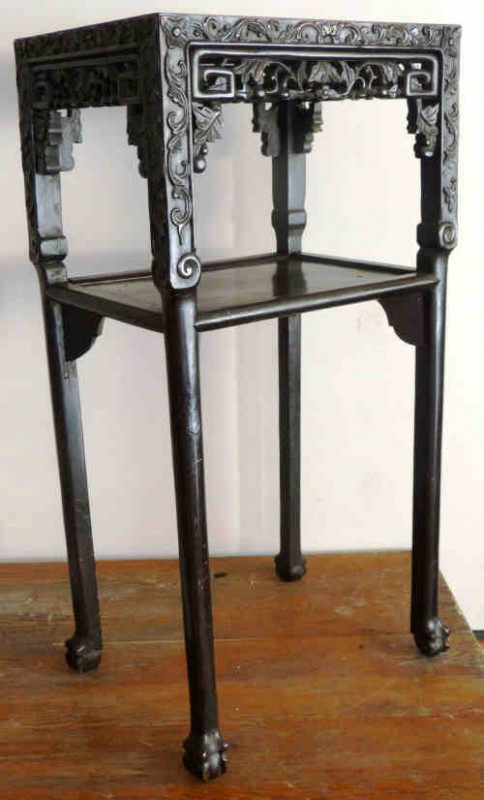 A Chinese hardwood and marble stand, circa 1900, the rectangular marble inset top above a leaf carved frieze over a similarly carved and pierced apron, raised on four legs, joined by a shelf stretcher, terminating in ball and claw feet. 0.80m by 0.42m by 