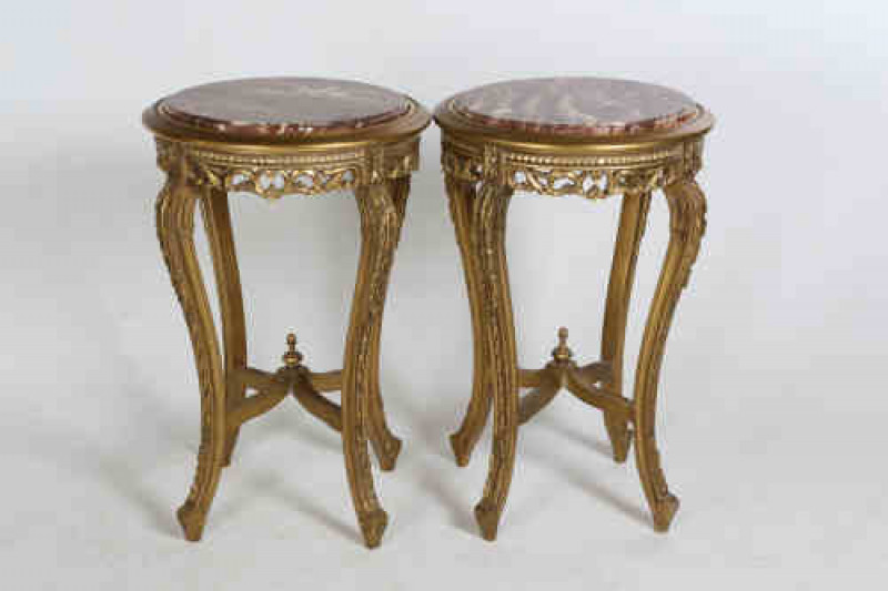 A pair of giltwood and marble tables, the circular moulded tops enclosing a marble surface, over a pierced and C-scroll apron, raised on elongated S-scroll legs embellished with acanthus, joined by an X-stretcher.