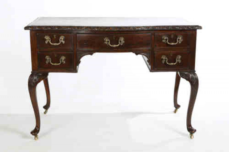 A Chippendale style mahogany desk, early 20th century, the gilt tooled leather inset rectangular top with bowed front and floral and ribbon carved edge, over two pairs of short drawers flanking a drawer over a kneehole, all fitted with Rococo style cast b