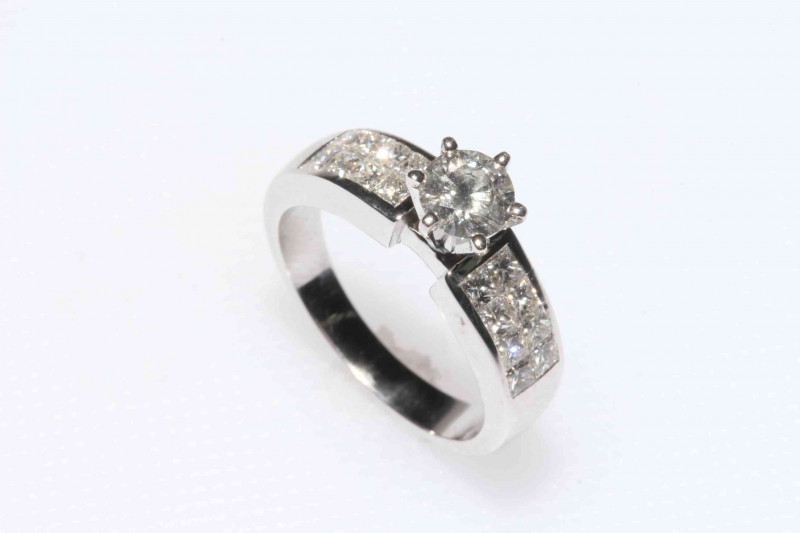18 carat white gold diamond engagement ring having elevated 0.5 carat diamond with eight brilliants to either side, size K/L.