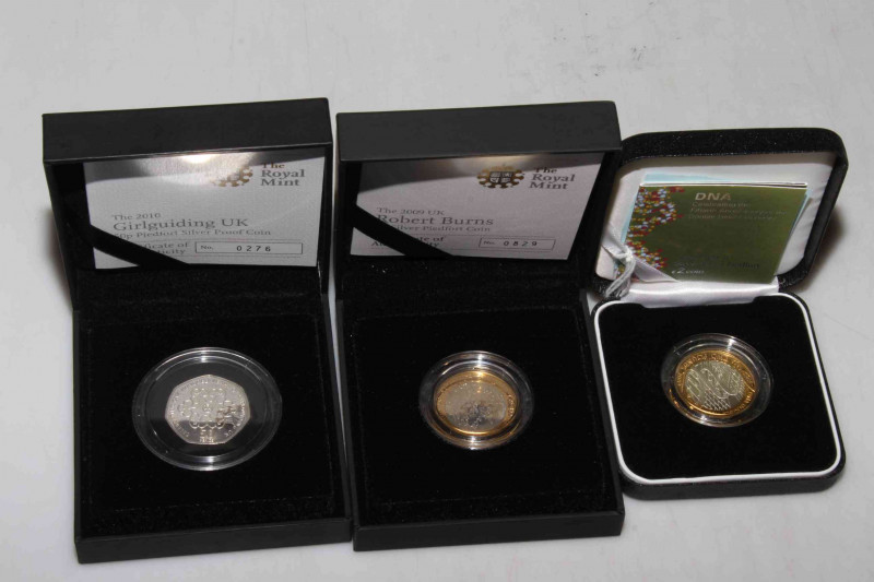 Three silver proof piedfort coins by The Royal Mint. Including £2 DNA Double Helix Discovery, 2010 UK Girlguiding 50p and 2009 Robert Burns UK £2. All boxed with COAs.