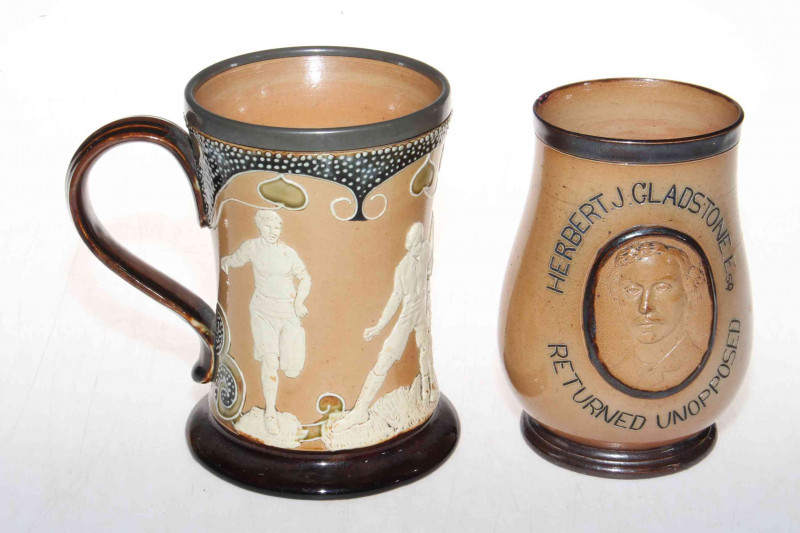 Doulton Lambeth stoneware 'sporting' mug with relief decoration, 15cm, together with Gladstone Leeds Election 1880 baluster beaker (2).