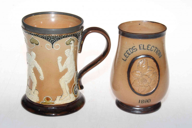 Doulton Lambeth stoneware 'sporting' mug with relief decoration, 15cm, together with Gladstone Leeds Election 1880 baluster beaker (2).
