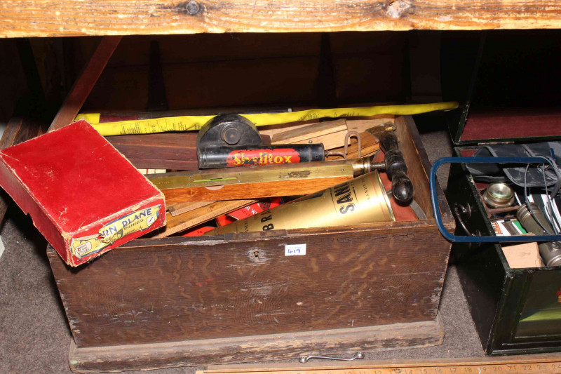 Three boxes of tools including levels, saws and tool auction catalogues.