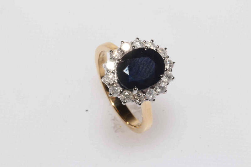 Sapphire and diamond 18 carat gold cluster ring, having oval 4 carat sapphire bordered with brilliant cut diamonds, size N.
