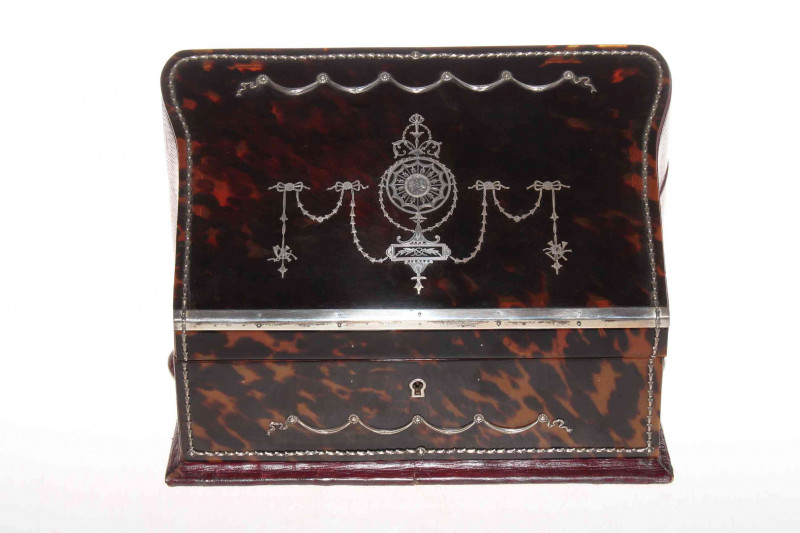Good silver inlaid tortoiseshell stationery box, the sloping lid inlaid with garlands and revealing fitted interior, 29cm wide, 20cm high.