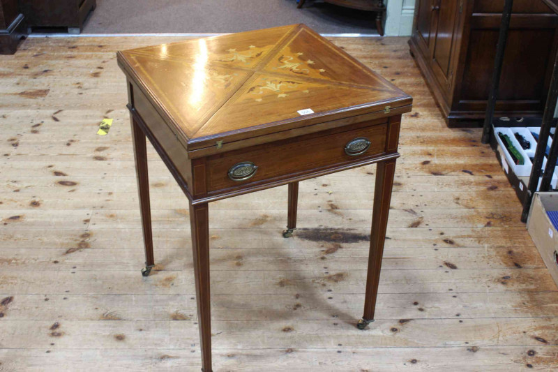 Edwardian inlaid mahogany envelope card table on square tapering legs bearing label for W.F. Greenwood & Sons, York, 74cm by 55.5cm by 55.5cm (closed).