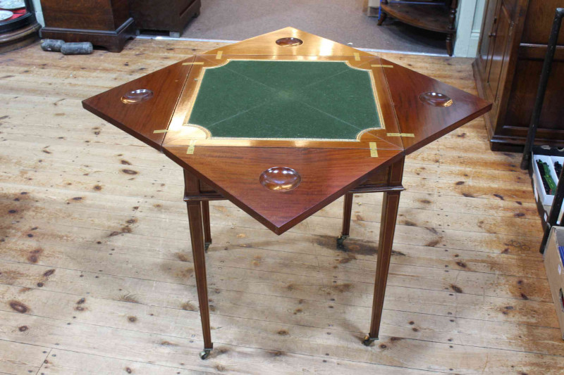 Edwardian inlaid mahogany envelope card table on square tapering legs bearing label for W.F. Greenwood & Sons, York, 74cm by 55.5cm by 55.5cm (closed).