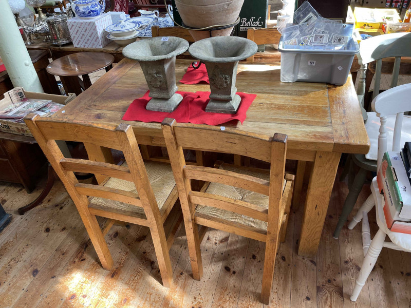Rectangular rustic style oak dining table with frieze drawer together with a set of four rush seated ladder back dining chairs (table 76cm by 130cm by 75cm).