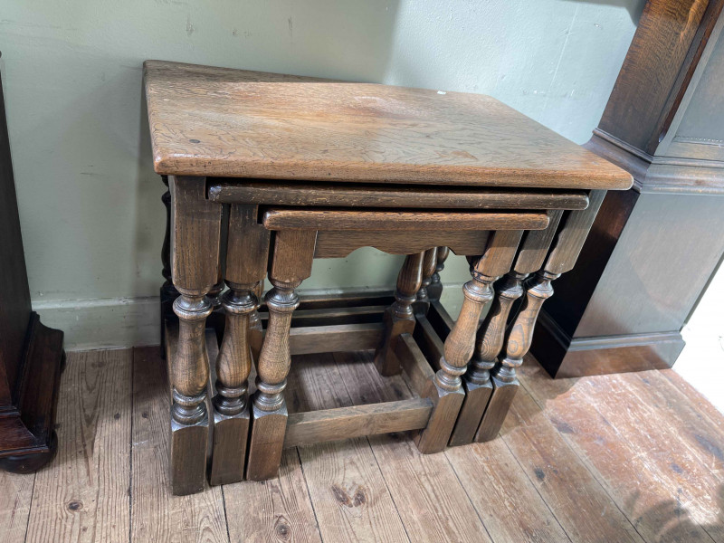 Oak nest of three turned leg tables (largest 48cm by 55cm by 35cm).