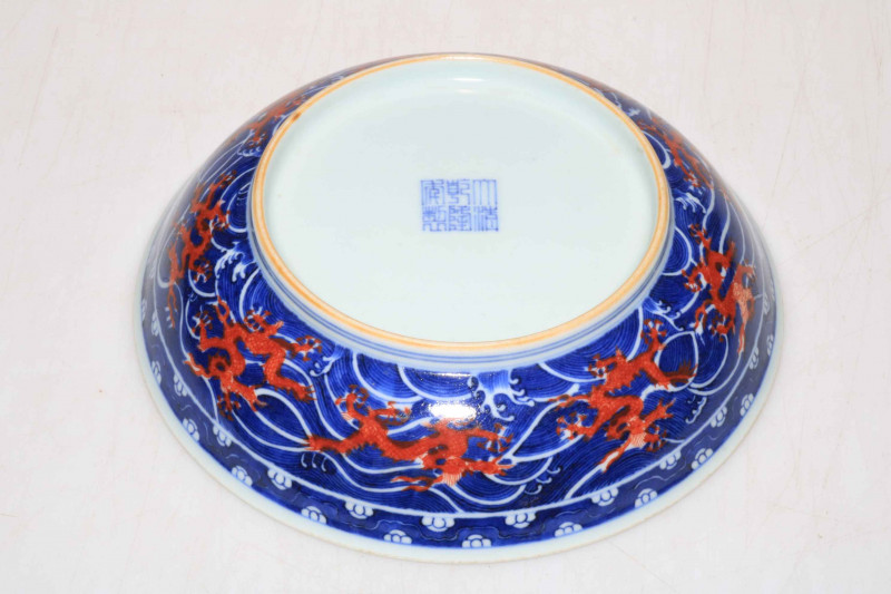 Chinese porcelain blue and white saucer dish decorated with internal red dragon, Qianlong mark to base, 18.5cm diameter.