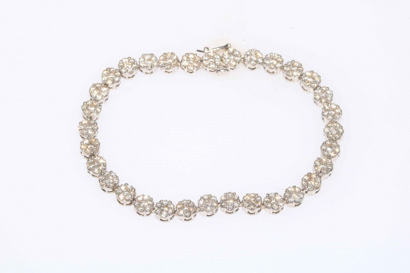 Spectacular diamond tennis bracelet in white gold and having 32 florets of seven brilliant cut diamonds, 18cm length.