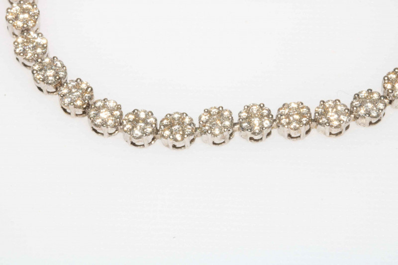 Spectacular diamond tennis bracelet in white gold and having 32 florets of seven brilliant cut diamonds, 18cm length.