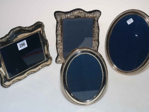 Four silver easel photograph frames, two oval and two ornate shaped.