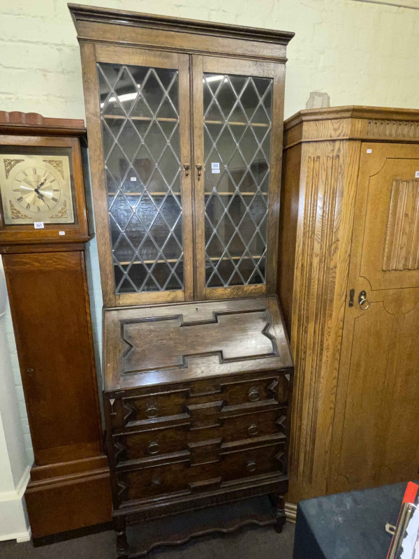 1920's oak bureau bookcase having two leaded glass doors above a fall front with three drawers below, 215cm by 76cm by 41cm.