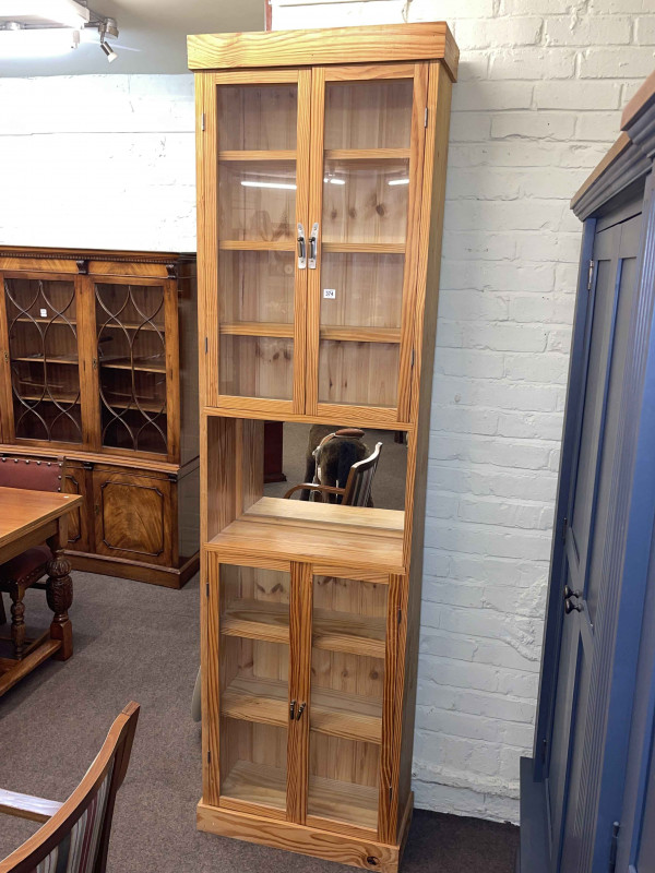 Tall pine glazed four door cabinet, 232cm by 65cm by 27cm.