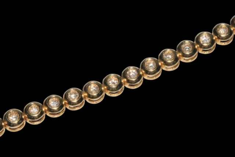 18 carat yellow gold rubover design tennis bracelet with a total of 34 round brilliant cut diamonds, 18cm long.