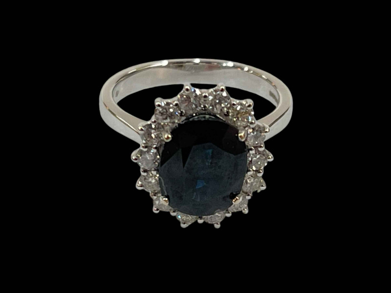 18 carat white gold claw set oval sapphire and diamond cluster ring, sapphire 3.90 carats, diamonds 0.50 carats.