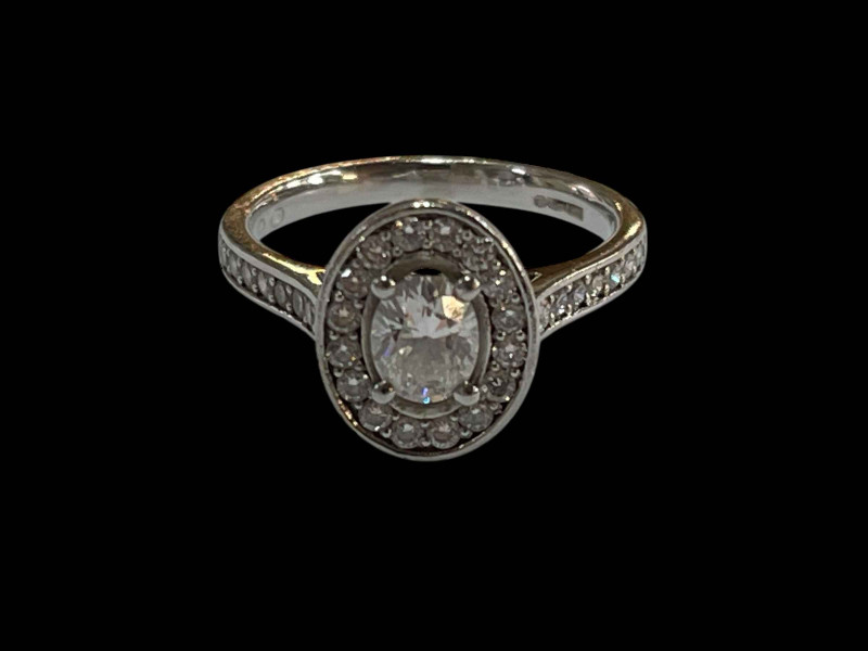 Platinum and diamond cluster ring, the central oval diamond 0.48 carats bordered by sixteen brilliant cut diamonds and further fourteen set into the shoulders, total diamond weight 0.90 carats, size K.