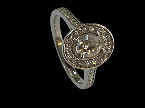 Platinum and diamond cluster ring, the central oval diamond 0.48 carats bordered by sixteen brilliant cut diamonds and further fourteen set into the shoulders, total diamond weight 0.90 carats, size K. thumbnail