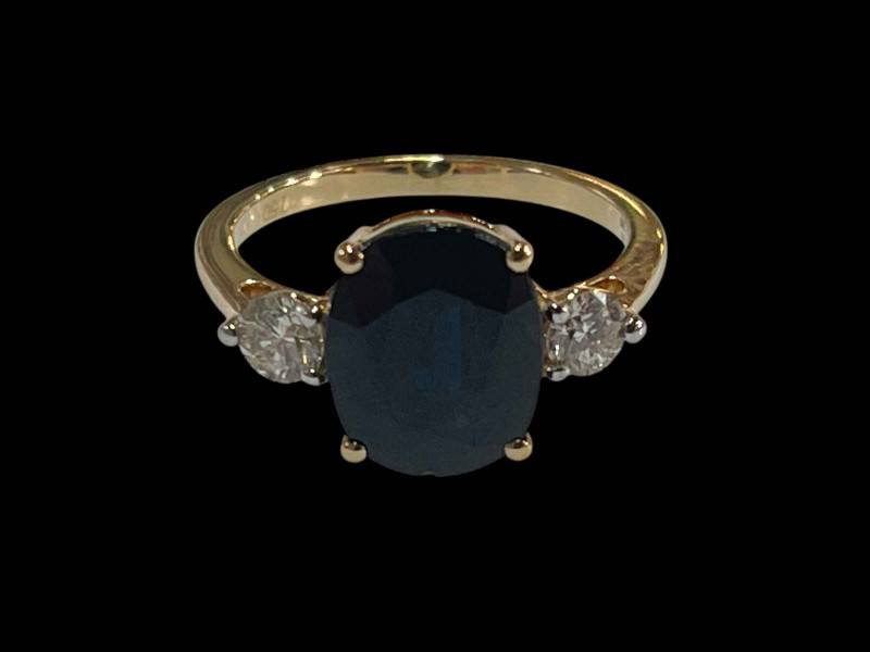 Sapphire and diamond three stone ring set in 18 carat yellow gold, the oval sapphire 2.75 carats flanked by diamonds totalling 0.38 carats, size L.