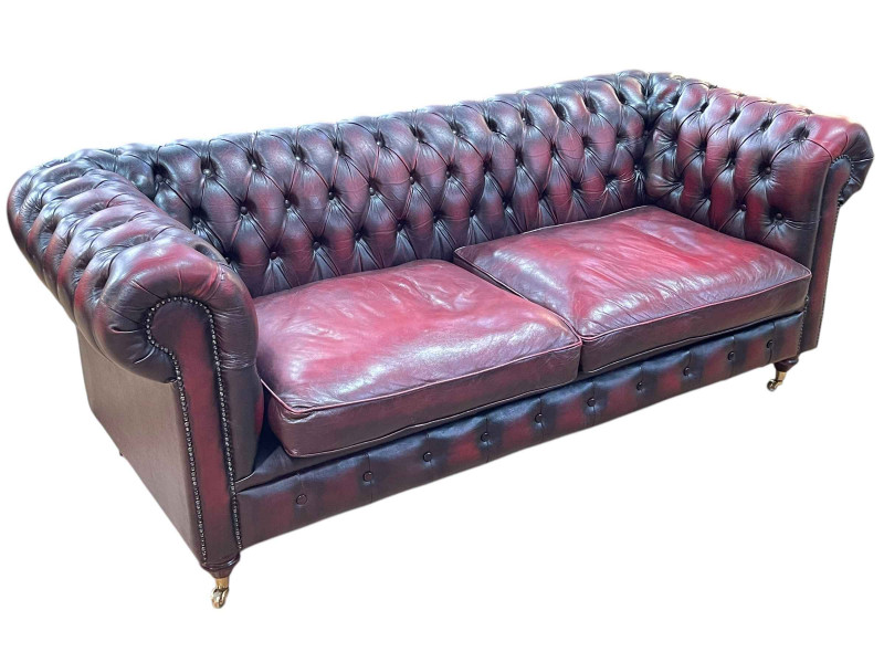 Ox blood buttoned leather and brass studded two seater Chesterfield settee, 76cm by 199cm by 86cm.