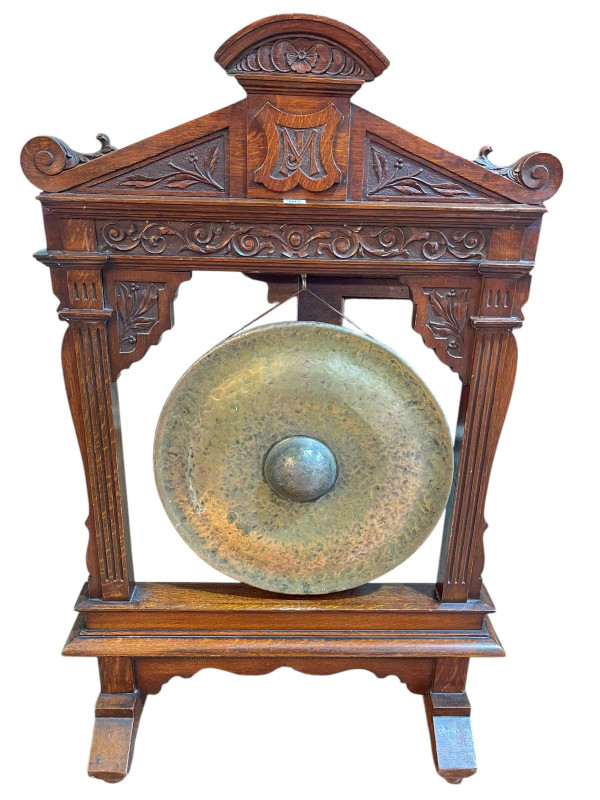 Victorian beaten brass dinner gong on carved oak stand, 130cm by 83cm by 27cm.