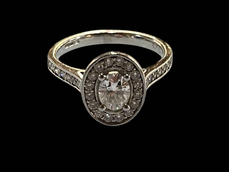 Platinum and diamond cluster ring, the central oval diamond 0.48 carats bordered by sixteen brilliant cut diamonds and further fourteen set into the shoulders, total diamond weight 0.90 carats, size K.