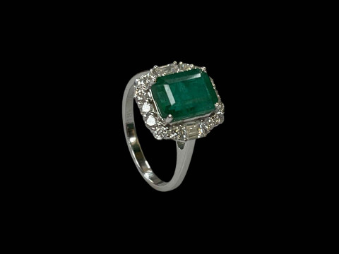Emerald and diamond cluster ring set in 18 carat white gold, the rectangular 3 carat baguette cut emerald surrounded by fourteen round cut and two baguette diamonds totalling 0.90 carats, size O. thumbnail
